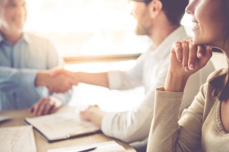 Business people working Cropped image of two handsome businessmen shaking their hands and smiling while working in office
