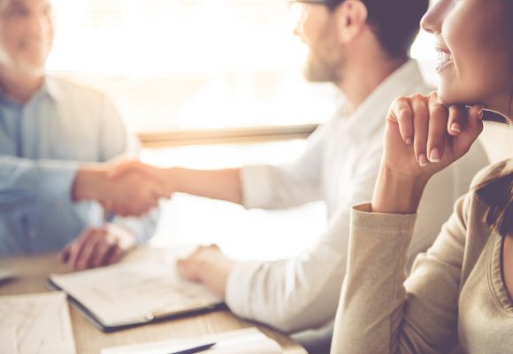 Business people working Cropped image of two handsome businessmen shaking their hands and smiling while working in office